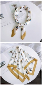 Détail d'un foulard en soie blanche avec motifs hiboux et bordure jaune gingembre