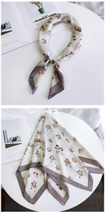 Détail d'un foulard en soie à motif hibou beige avec bordure violette sur table
