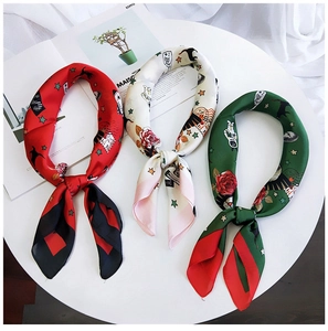 Detailed close-up of three printed silk scarves in red, cream, and green on a white tray