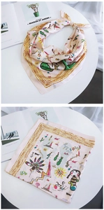 Detail of pink silk-feel scarf with yellow wavy edge and colorful cartoon illustrations