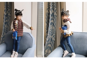 Kids plaid scarf paired with a white sweatshirt and bow headband in a cozy home setting