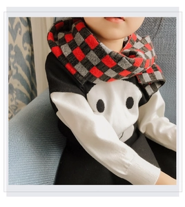 Detailed close-up of child's plaid knit scarf paired with a black and white sweater