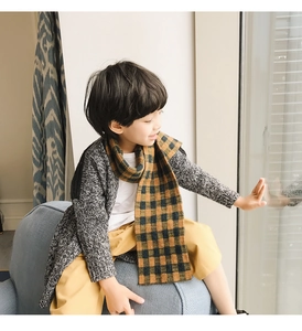 Close-up of child wearing a thick yellow and black checkered scarf with grey knit cardigan