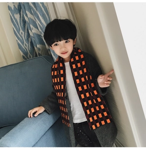 Detail of child wearing a thick orange and black checkered knit scarf with a grey coat