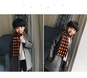 Detail shot of a thick knitted orange checkered scarf for kids with a soft fringe edge