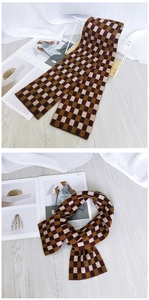 Macro view of thick checkered pattern scarf in brown and white winter knit fabric