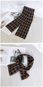 Detail of plaid knit scarf featuring orange and blue check pattern with soft texture