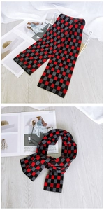 Detailed view of red and grey checkered knitted scarf on a light wooden floor background