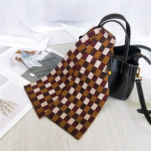 Classic British style checkered knit scarf in brown and red draped on a leather bag