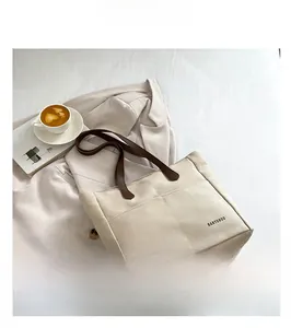 Detail of canvas tote bag featuring premium brown leather handles and HANYUNDUO logo pocket