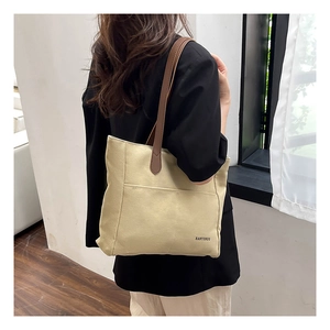 Detail of canvas tote bag with brown straps and side pocket in minimalist interior