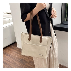 Detailed shot of large cream canvas tote bag with brown leather straps on shoulder