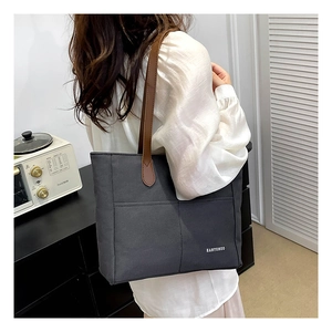 Charcoal grey large canvas tote bag with long brown leather handles worn by a woman