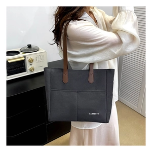 Detail of dark grey canvas tote with brown leather handles and front pockets