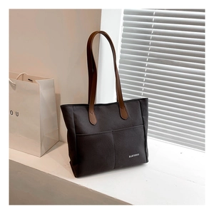 Detail of grey canvas tote bag featuring dual front pockets and brown leather handles