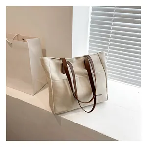 Detail of minimalist beige canvas tote bag with large front pocket and brown straps