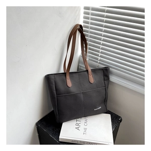 Detail of grey canvas tote bag featuring brown leather handles and HANYUNUO logo