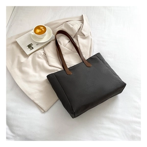 Minimalist canvas tote bag with brown leather straps shown in a professional lifestyle setting