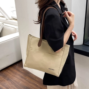 Japanese style beige canvas tote bag with brown leather straps shown on a model