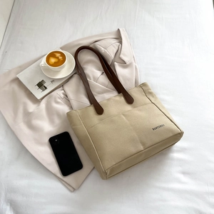Large khaki canvas tote bag with brown leather handles for casual daily commuting