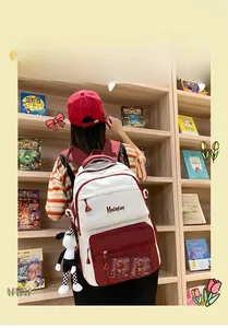 Détail du sac à dos rouge et blanc avec pendentif chien à carreaux dans une librairie