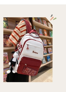 Détail d'un grand sac à dos rouge et blanc avec pendentif mouton dans une bibliothèque
