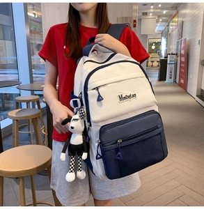 Détail du sac à dos en toile bleu et blanc avec logo MonDayLucy et pendentif chiot