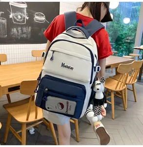 Gros plan sur le sac à dos blanc et bleu avec poches multiples et breloque cartoon