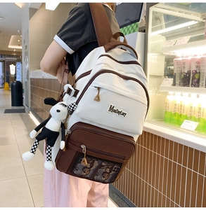 Détail d'un sac à dos en nylon beige avec accents bruns et porte-clés chien en peluche