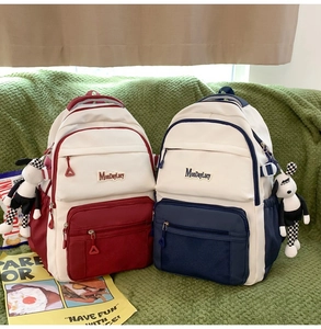 Détail de grands sacs à dos scolaires en rouge et bleu avec pendentifs chien