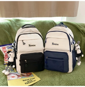 Détail de sacs à dos en nylon bicolores noir et bleu avec breloques chien en peluche