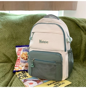 Détail frontal du sac à dos beige et vert avec étiquette et poche en filet
