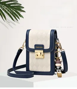 Close-up of beige quilted crossbody bag with navy blue trim and gold metal lock
