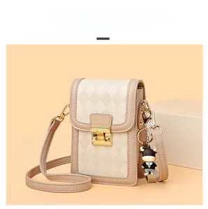 Detail of rhombic textured crossbody phone bag with gold clasp and cartoon cow charm