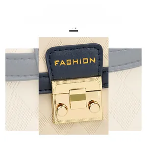 Detail of golden twist lock hardware on quilted cream leather bag with navy blue strap