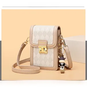 Detail of rhombic embossed cross-body phone bag with metal clasp and cute cartoon charm