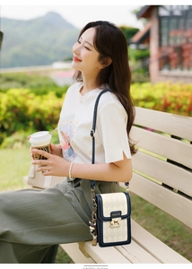 Detail of cream and navy quilted leather crossbody bag with gold metal turn-lock