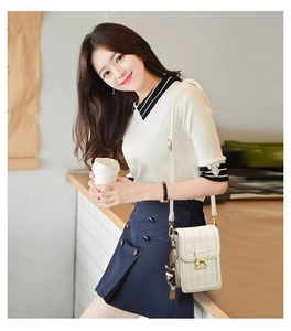 Detail of white quilted crossbody phone bag with gold clasp and fashion plaque on model