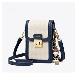 Detail of navy and beige quilted crossbody phone bag with gold clasp and bull charm