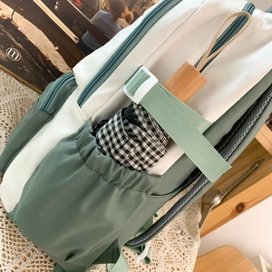 Sac à dos patchwork vert et crème avec poche latérale contenant un parapluie à carreaux