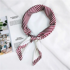 Close-up of red and white striped square silk scarf tied in a stylish decorative bow