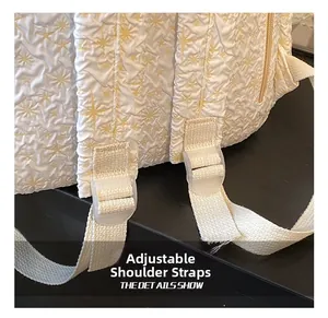 Detail van de verstelbare schouderriem en gesp op de witte rugzak met geplooide textuur