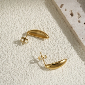 Polished gold crescent moon stainless steel earrings on a minimalist stone background