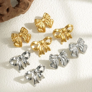 Bow-knot 18k gold hollow stainless steel earrings in gold and silver on textured background