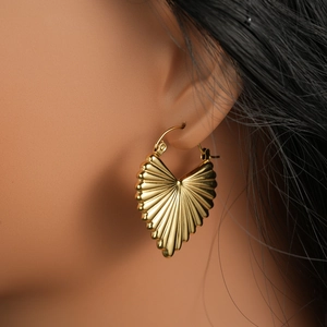 Gros plan de boucles d'oreilles créoles dorées en forme de cœur à texture plissée radiale