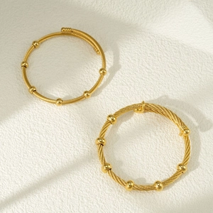 Dettaglio macro di due bracciali rigidi a treccia placcati oro 18k con perle lisce
