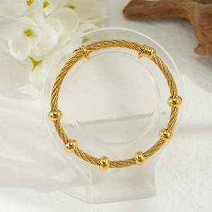Dettaglio macro del bracciale in filo d'oro 18k con perline di metallo lucido