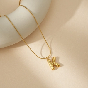 Detalle del colgante de letra K en 3D dorado con una elegante cadena de serpiente