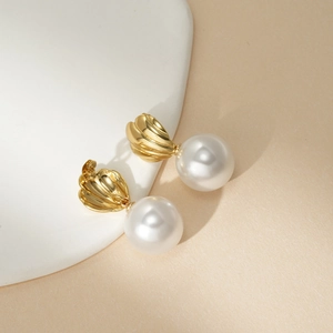 Elegant 18k gold shell design earrings with white pearls on a minimalist ceramic stand