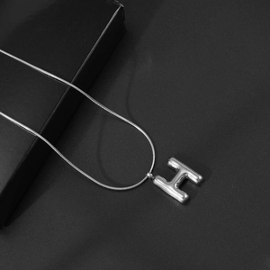Macro-opname van 3D bubble letter H hanger aan een hoogglans zilveren slangenschakel